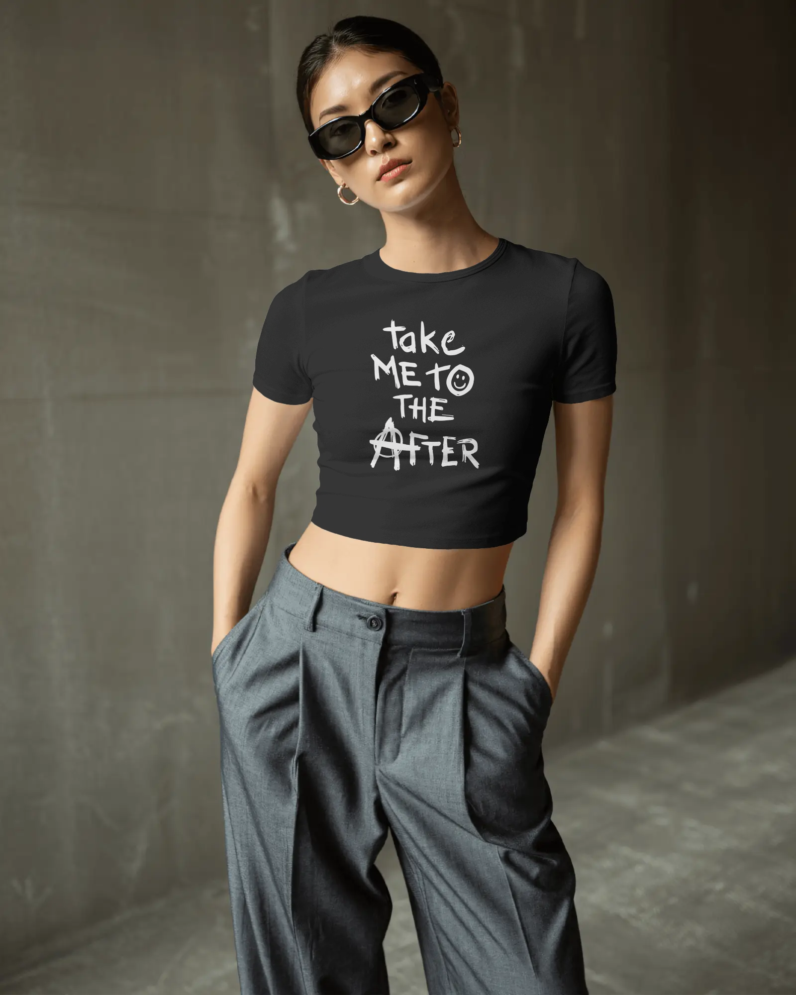 Person wearing a black t-shirt with text and gray pants against a plain background